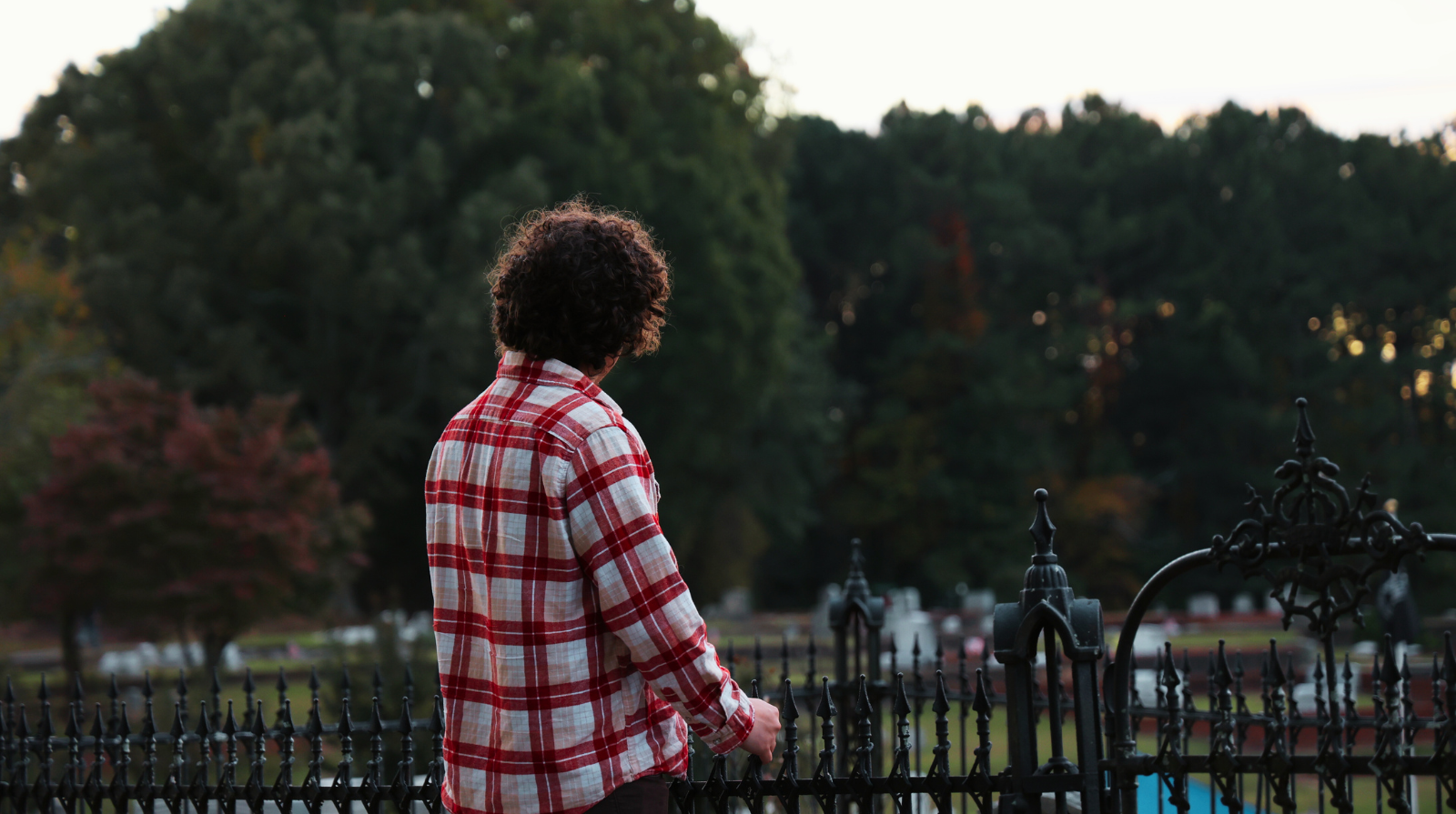 Man standing in a cemetery looking at the sunset.